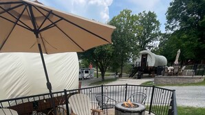 Un patio al aire libre con una chimenea, dos sillas Adirondack y un paraguas grande.