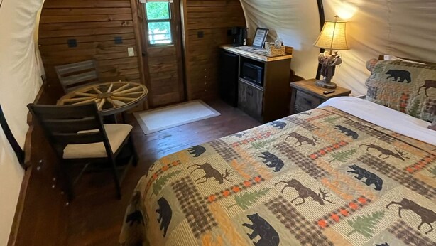 Una habitación con tienda de campaña acogedora, con cama, escritorio, silla y lámpara.