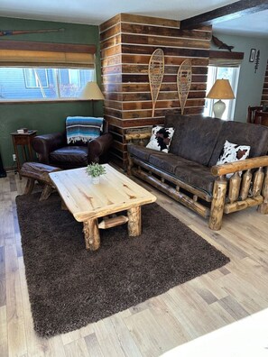 A rustic living room with a wooden coffee table, leather sofa, and a dark rug. - Mammoth Manor at Snow Creek (Mammoth Lakes)