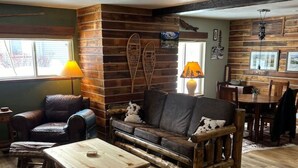 Ett mysigt vardagsrum med en soffa i trä, ett soffbord och en matplats med stolar och ett bord, allt i trä.