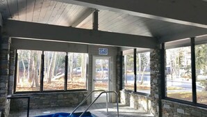 En inomhuspool med en skylt som uppmanar att hålla grinden stängd, stenmurar och stora fönster.