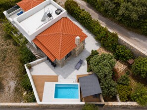 A modern house with a swimming pool, a covered patio, and a stone chimney.