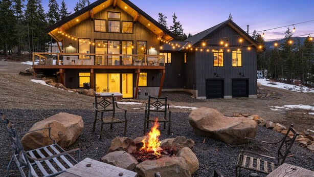 A large log cabin with a deck and a fire pit, surrounded by rocks and trees. - Huge game room, Hot tub, Sleeps 16+ with Bonus loft, ATV Snowmobile Trails (Cle Elum)