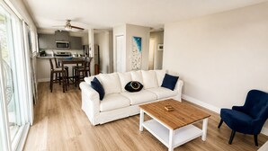 A modern living room with a white sofa, a coffee table, and a blue armchair. - Spacious South Bay Condo (Torrance)