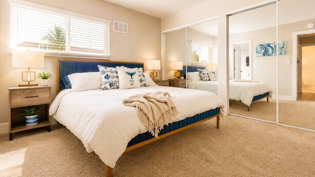 A bedroom with a bed, bedside tables, a mirror, and a window with blinds. - Spacious South Bay Condo (Torrance)