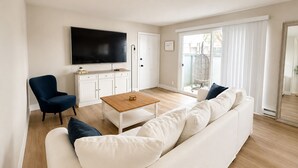 A modern living room with a flat-screen TV, a sofa, a coffee table, and a chair. - Spacious South Bay Condo (Torrance)