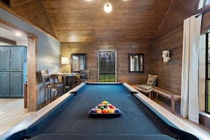 A pool table in a room with wooden walls, a bench, and a table with chairs. - Creekside Ranch - Big Yard, Hot Tub, Fire Pit, Game Room, Pet-Friendly (Broken Bow)