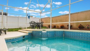A swimming pool with a blue tiled edge, surrounded by a white fence, and a table with chairs outside. - Cozy Oasis 5BR Near Disney with private pool (Kissimmee)