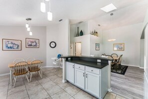 A modern kitchen with a central island, white cabinets, and a dining area with a table and chairs.