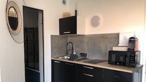 A compact kitchen with a black countertop, a sink, a stove, and a microwave.