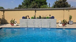 A swimming pool with a stone wall and swan-shaped planters. - Cottage - Sleeps 4 - Pool - Near Airport (Harare)