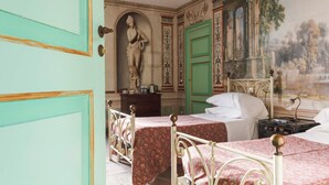 A room with two beds, a green door, a statue, and a mural. - AGRITURISMO CASTELLO BECCARIA (Pieve del Cairo)