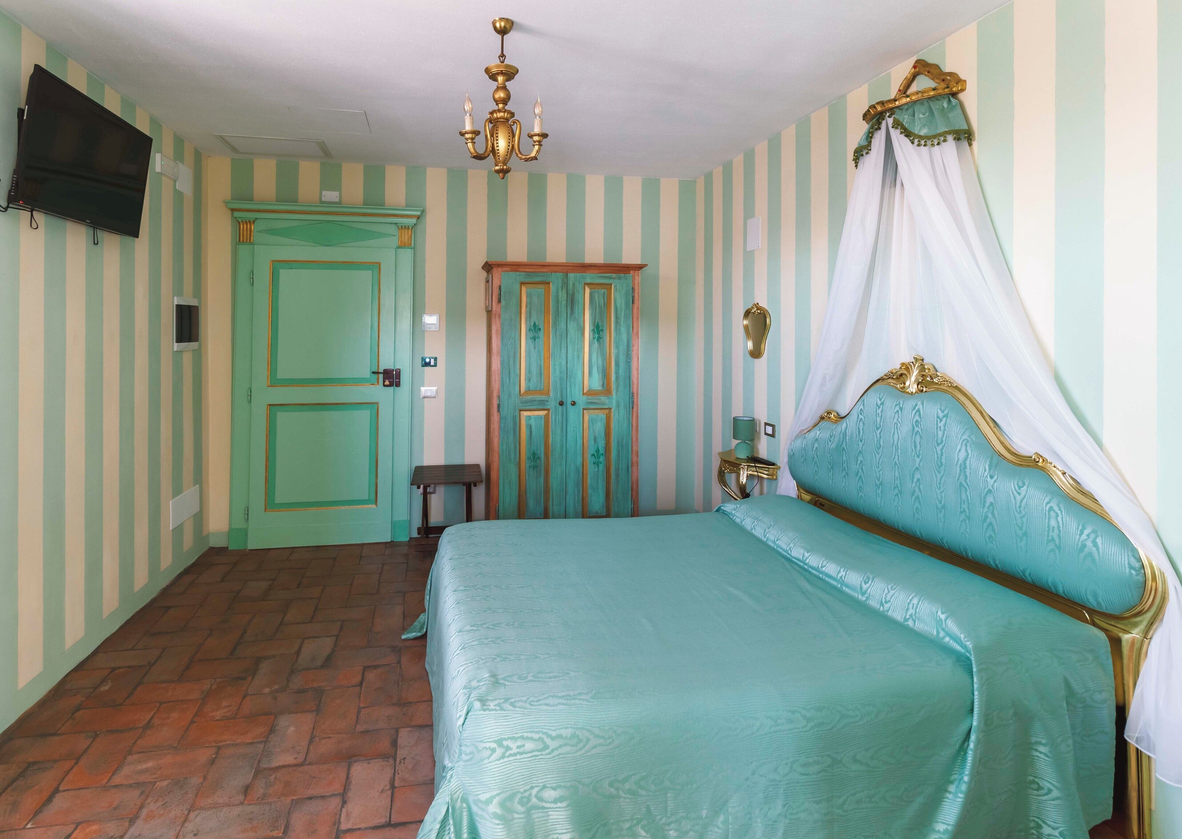 Un dormitorio con cama, televisor, candelabro y paredes a rayas.