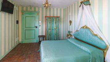 Un dormitorio con cama, televisor, candelabro y paredes a rayas.