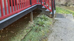 A wooden deck with red railings leading to a covered porch with a staircase. - Cozy quiet romantic cabin for 2, Fully equipped modern kitchen. Pleasant patio. (Sevierville)