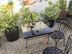 Eine kleine Terrasse im Freien mit Tisch und Stühlen, umgeben von Blumentöpfen.