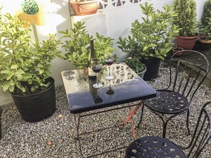 Une petite terrasse extérieure avec une table et des chaises, entourée de plantes en pot.