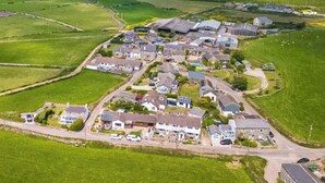 An aerial view of a residential area with houses, roads, and fields. - This cosy cottage is an ideal base for you and your dogs. (St Just)