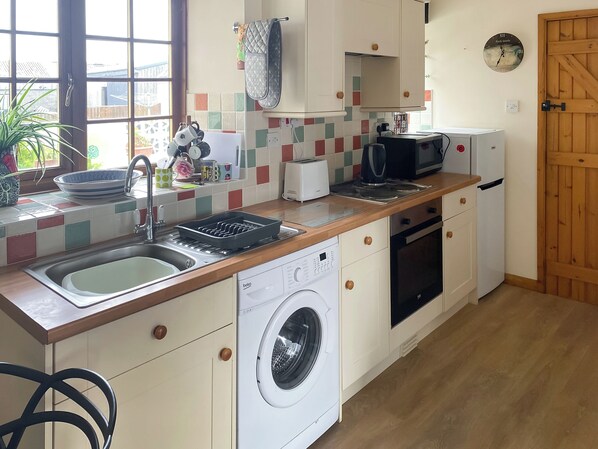 Une cuisine compacte équipée d’un lave-linge, d’un grille-pain et d’un four à micro-ondes.