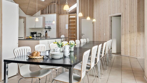 Een moderne keuken met witte kastjes, een zwart aanrecht en een houten plafond.