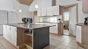 Een moderne keuken met witte kastjes, een centraal eiland en hanglampen.