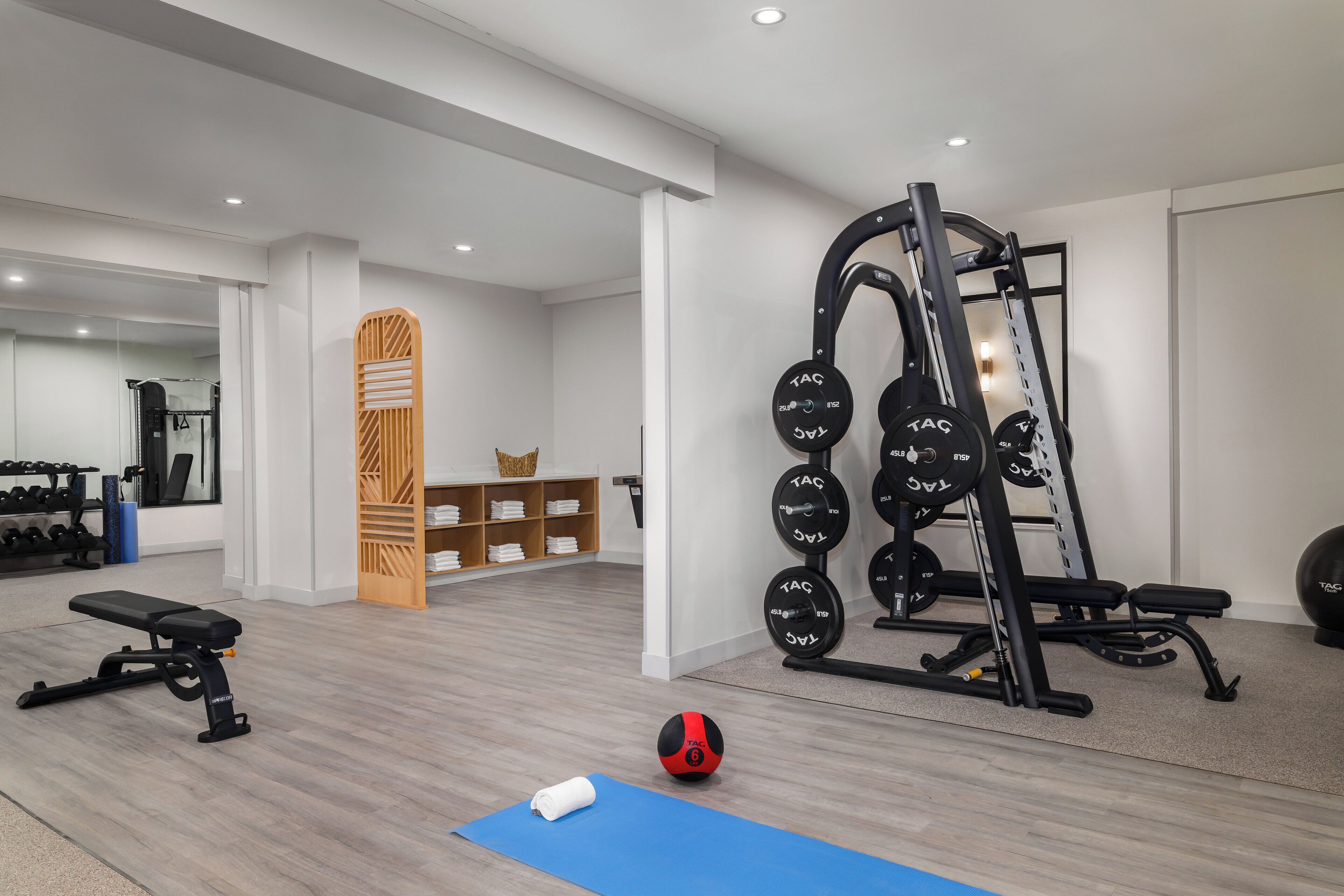 Ein modernes Fitnessstudio mit Gewichte, Trainingsmatten und einer Bank.