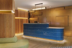 A reception area with a blue tiled counter, wooden paneling, and a green sofa.