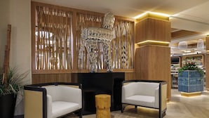A modern lobby with two white sofas, a wooden accent wall, and a decorative sculpture. - EVEN Hotel Detroit North - Troy (Troy)