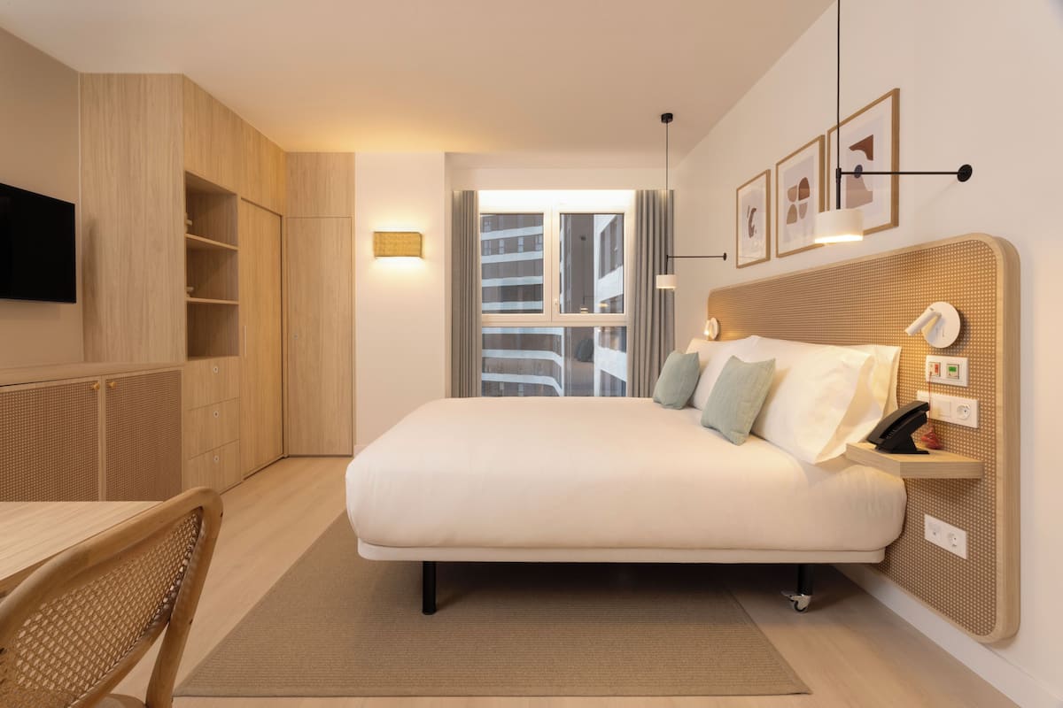 A modern hotel room with a large bed, a desk, and a TV.