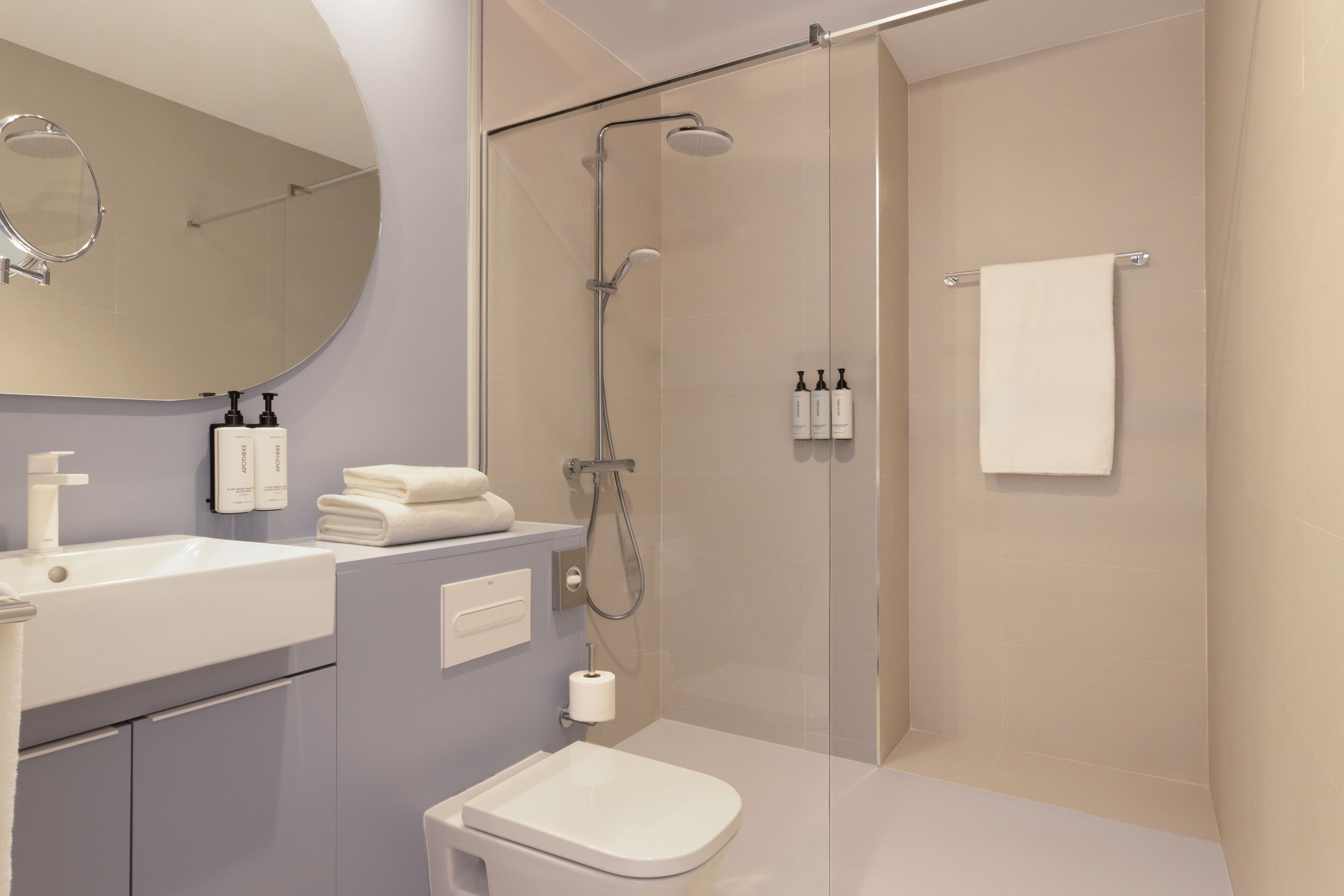 Un baño moderno con ducha de vidrio, un lavabo blanco y un inodoro.