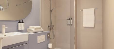 Un baño moderno con ducha de vidrio, un lavabo blanco y un inodoro.