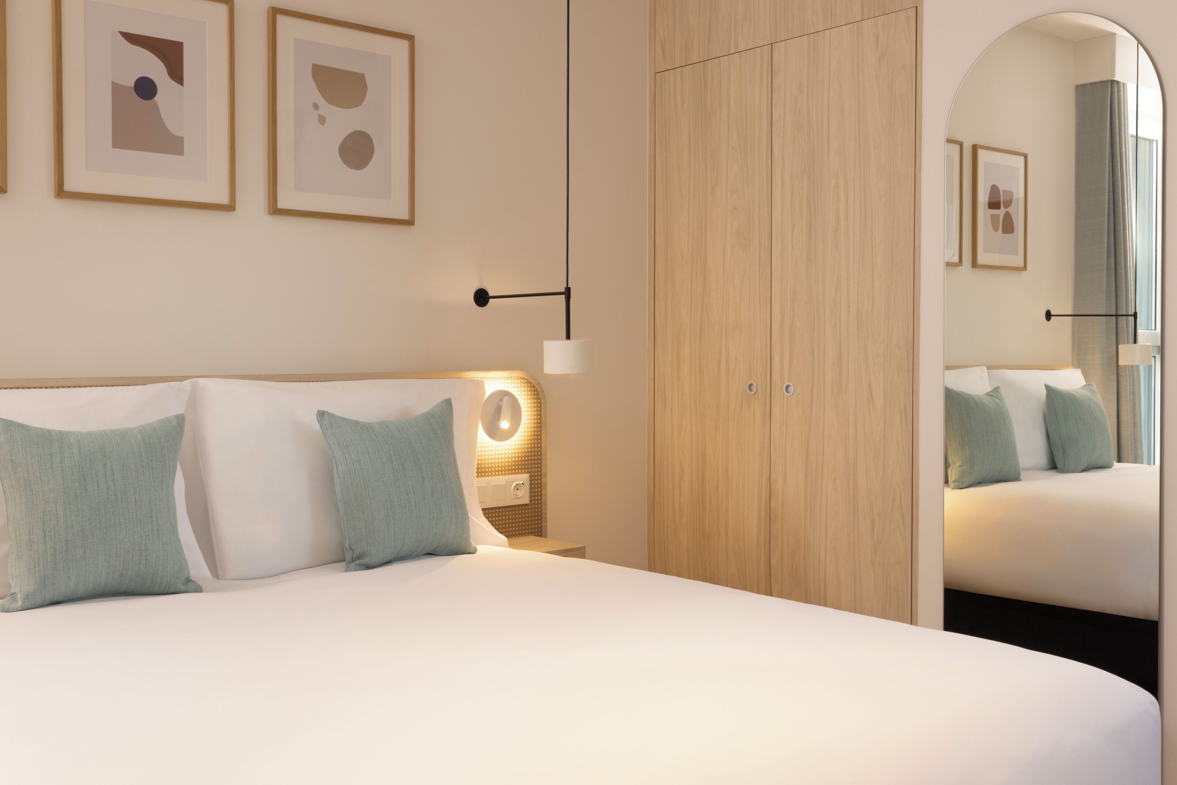 Quarto de hotel moderno com uma cama grande, um guarda-roupa e um espelho.