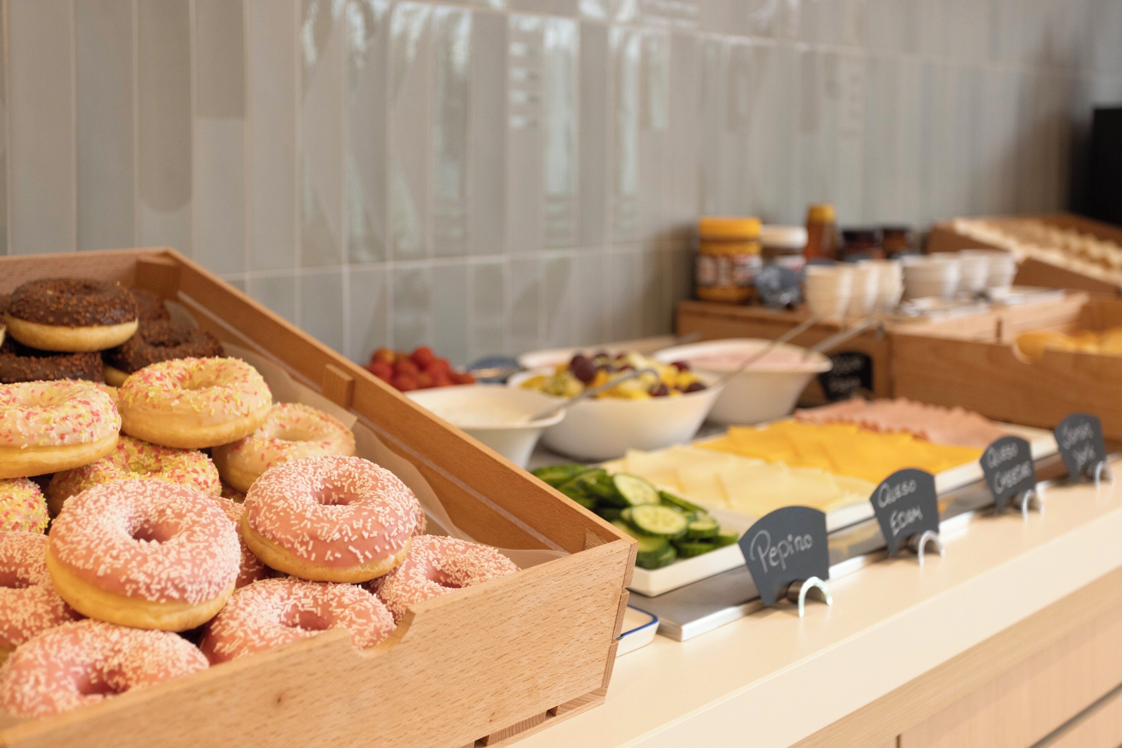 Een buffet met diverse gerechten, waaronder donuts, salades en kaas.