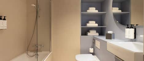 Un bany modern amb dutxa protegida per vidre, un vàter i un lavabo amb prestatges per a productes de tocador.