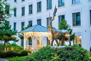 Un edificio con fachada moderna, una escultura central de un animal y un pabellón decorativo.