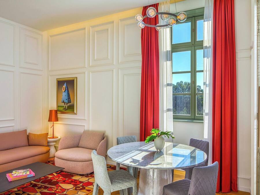 A living room with a sofa, armchair, round table, and a painting on the wall.