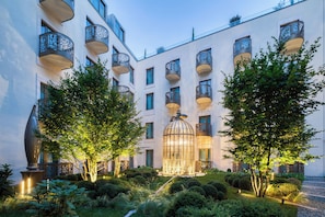 A courtyard with a glass-enclosed structure, surrounded by trees and a well-maintained garden. - Kimpton BEM Budapest by IHG (Budapest)