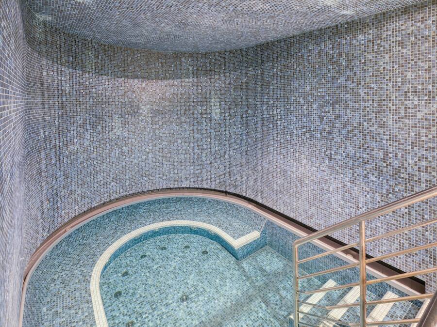 Una piscina con revestimiento de azulejos y una escalera metálica que conduce a un nivel superior.