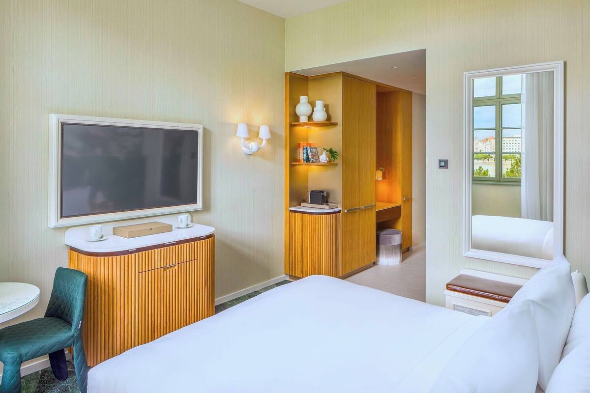 Ett hotellrum med en säng, en TV, ett skrivbord och en sittgrupp.