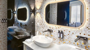 Une salle de bain moderne avec deux lavabos, un grand miroir et un pare-feu en carreaux.