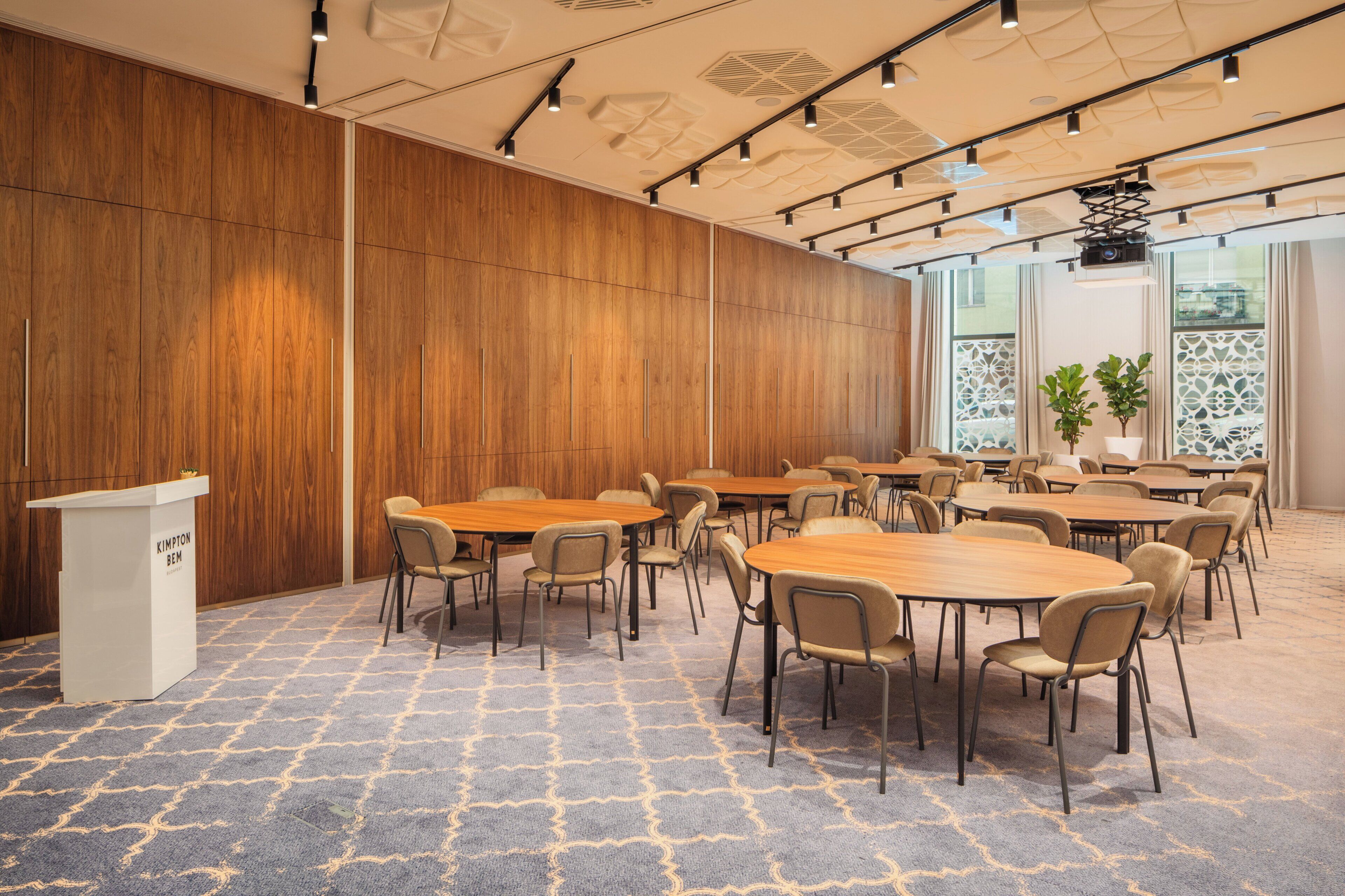 A conference room with wooden panel walls, a podium, and multiple tables with chairs.