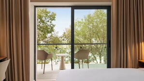 A hotel room with a large sliding glass door leading to an outdoor balcony with two chairs and a small table. - Holiday Inn Beja by IHG (Beja)