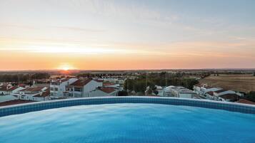 Una piscina con vista a una zona residencial y al atardecer.