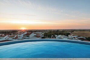 A swimming pool with a view of a residential area and the sunset.