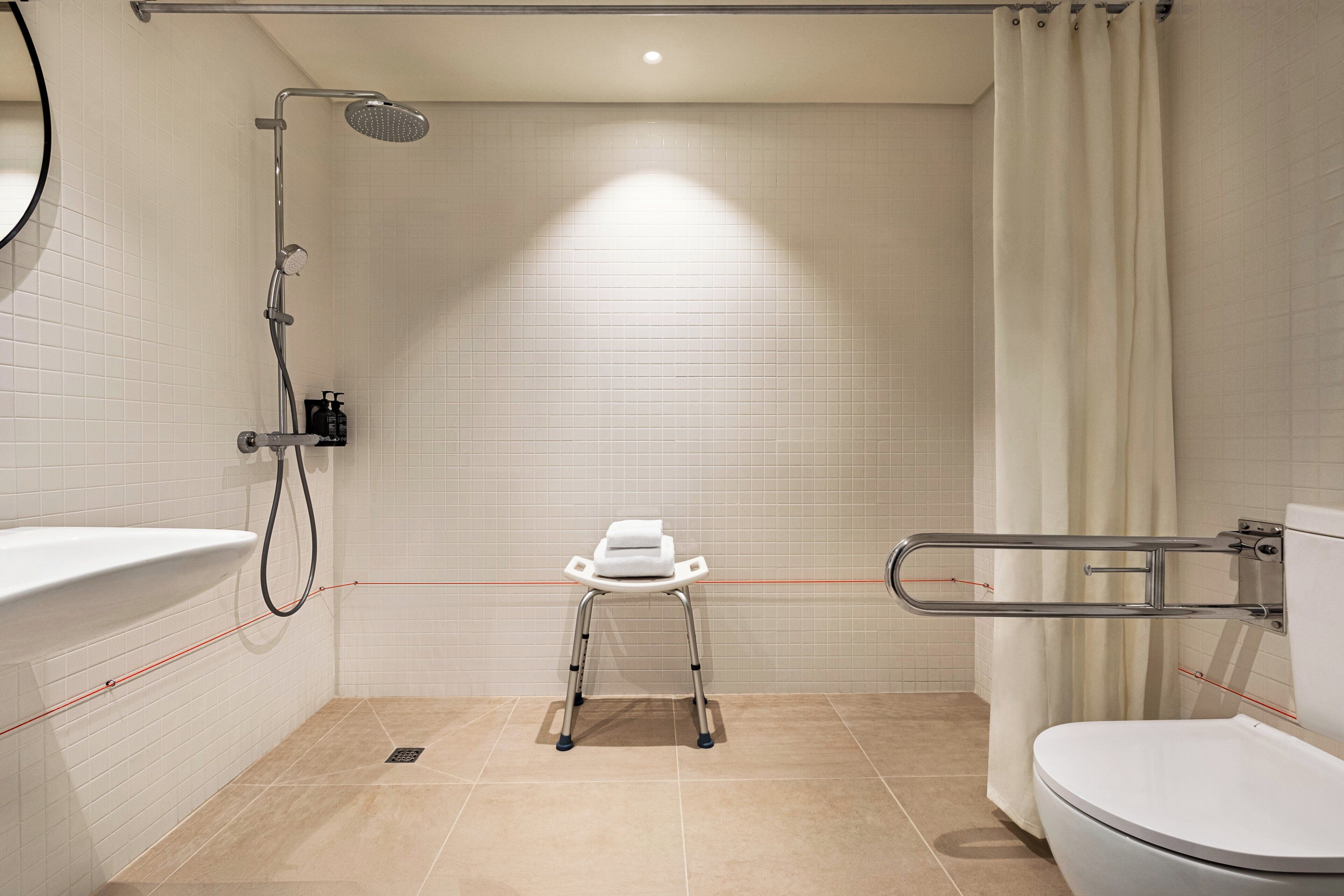 Une salle de bain avec une douche, des toilettes et un petit tabouret.
