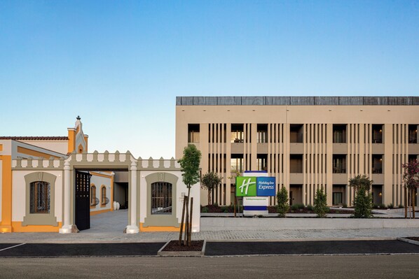 A Holiday Inn Express building with a modern facade, a gated entrance, and a landscaped area with small trees. - Holiday Inn Express Evora by IHG (Évora)