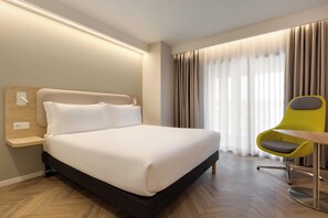 A hotel room with a large bed, a bedside table, a chair, and a window with curtains. - Holiday Inn Express Evora by IHG (Évora)