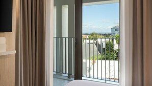 A hotel room with a large sliding glass door to the outside, a wooden floor, and a mounted flat-screen TV on the wall. - Holiday Inn Express Evora by IHG (Évora)