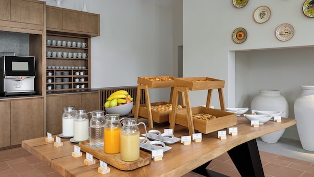 A breakfast buffet setup with various food items and beverages, including a bowl of fruit and several serving stations. - Holiday Inn Express Evora by IHG (Évora)