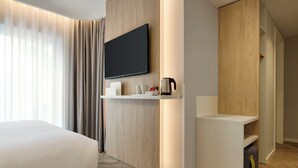 A modern hotel room with a large bed, a flat-screen TV mounted on the wall, a coffee maker, and a small seating area with a side table. - Holiday Inn Express Evora by IHG (Évora)